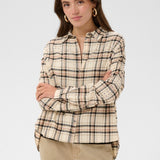 Woman wearing a plaid shirt and beige pants on a plain background