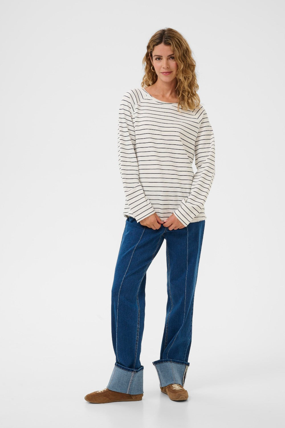 Woman wearing a striped long-sleeve shirt and blue jeans on a white background