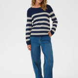 Woman wearing navy and white striped sweater with jeans on a white background