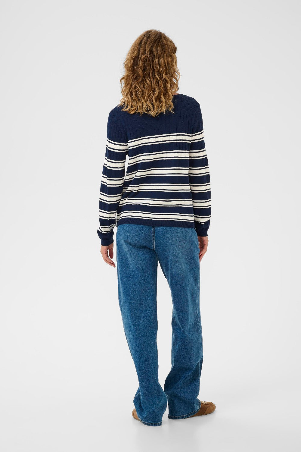 Person wearing a navy and white striped sweater and blue jeans on a white background