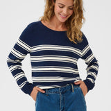 Woman wearing navy and white striped sweater with jeans on a white background