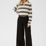 Woman wearing a black and white striped shirt with a collar and black wide-leg pants on a white background