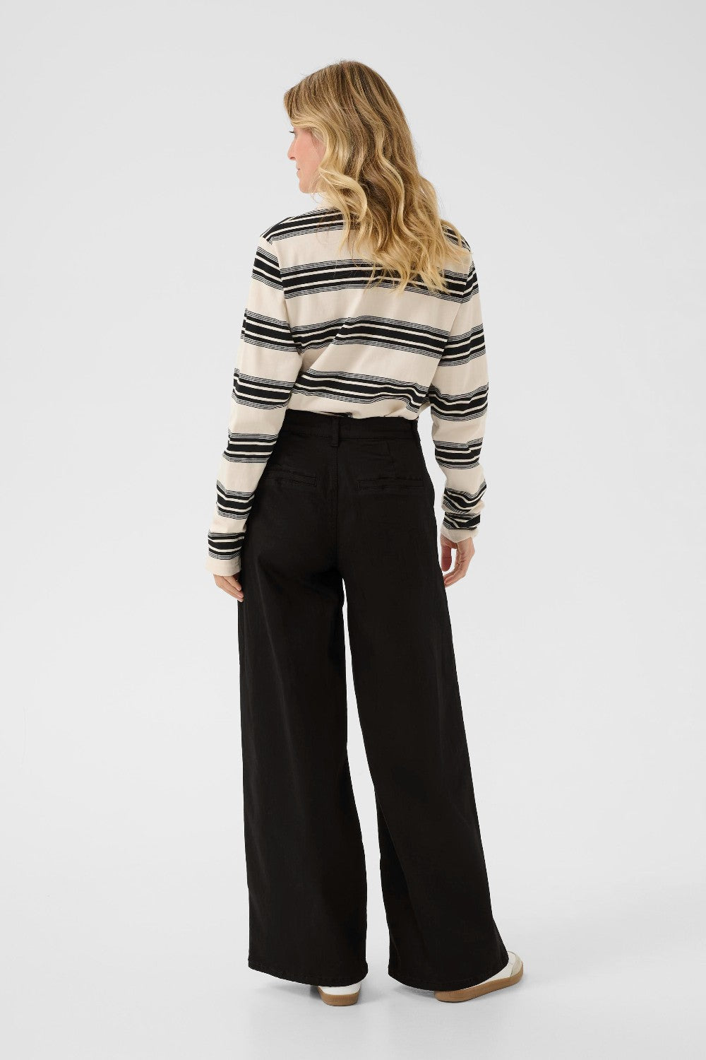 Woman wearing a striped sweater and black pants on a white background