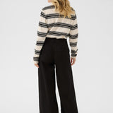 Woman wearing a striped sweater and black pants on a white background
