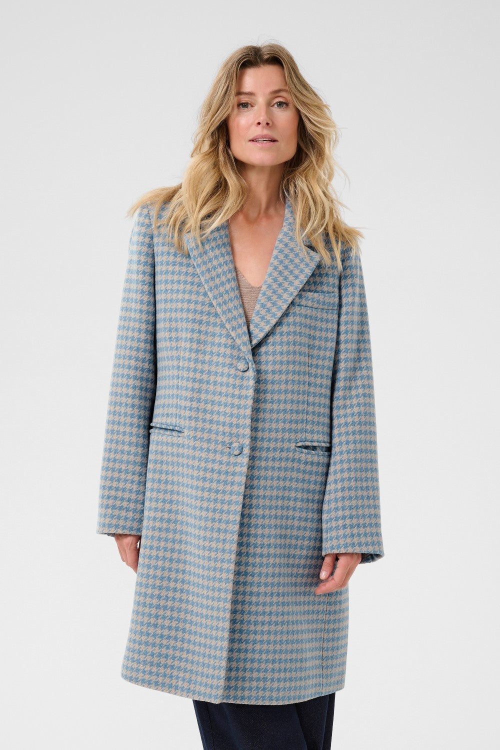 Woman wearing a blue checkered coat against a white background