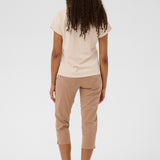 Person wearing a beige t-shirt and tan capri pants on a white background