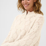 Woman wearing a cream knitted sweater against a white background