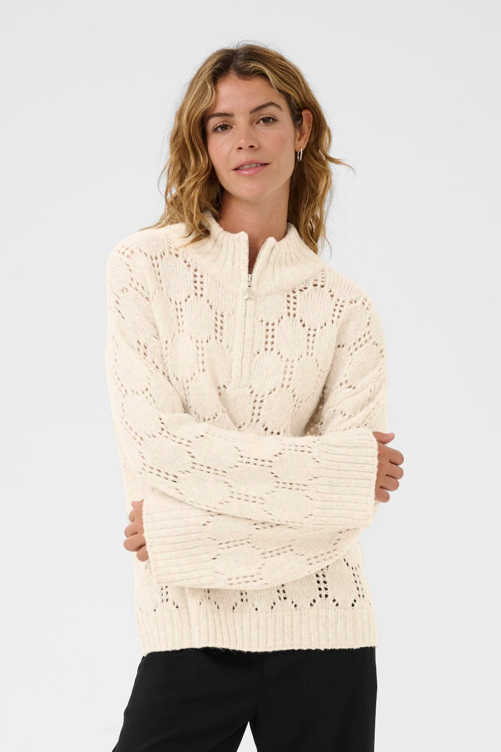 Woman wearing a cream knitted sweater against a plain background