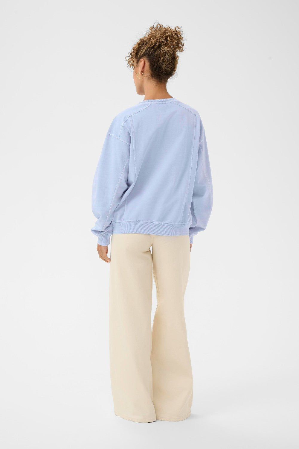 Person wearing a light blue sweater and beige pants on a white background