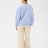Person wearing a light blue sweater and beige pants on a white background