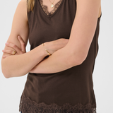 Woman wearing a brown sleeveless top with lace trim on a white background