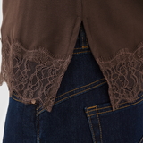 Brown lace-trimmed top over blue jeans on a white background