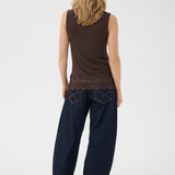 Woman wearing a brown sleeveless top and dark blue pants on a white background