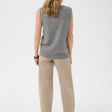 Woman wearing a sleeveless grey sweater with tan pants, shown from the back, against a light background.
