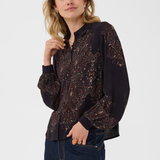 A woman modeling a dark long-sleeve button-up blouse with intricate paisley embroidery, paired with dark blue jeans against a plain light gray studio background.
