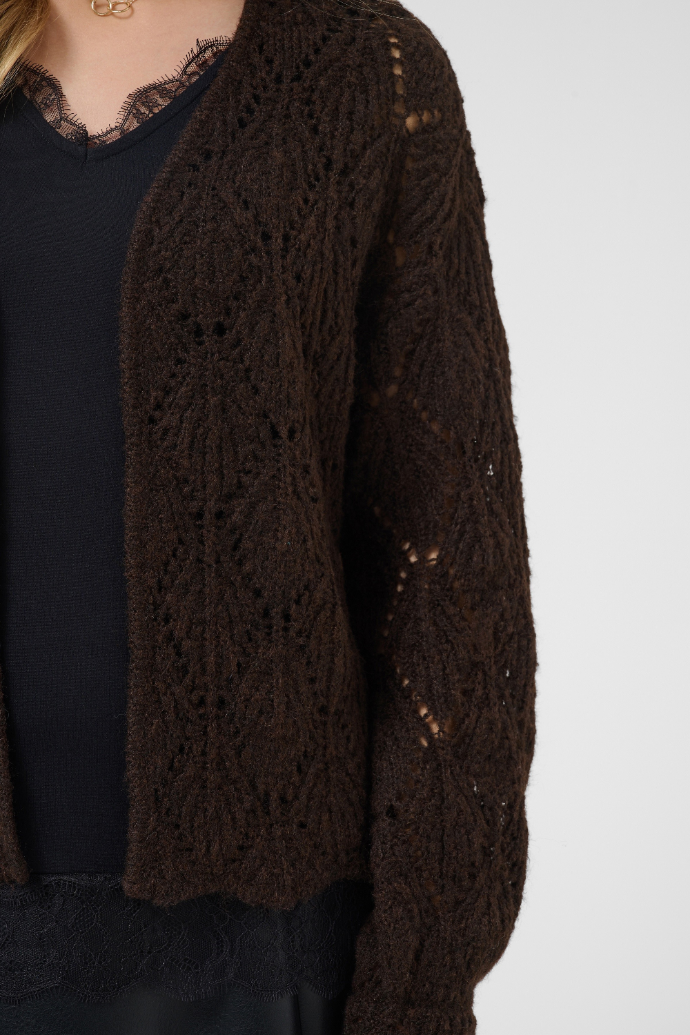 Brown cardigan over a black top on a white background