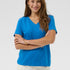 Woman wearing a blue shirt and white pants against a plain background