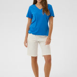 Woman wearing a blue shirt and white shorts on a plain background
