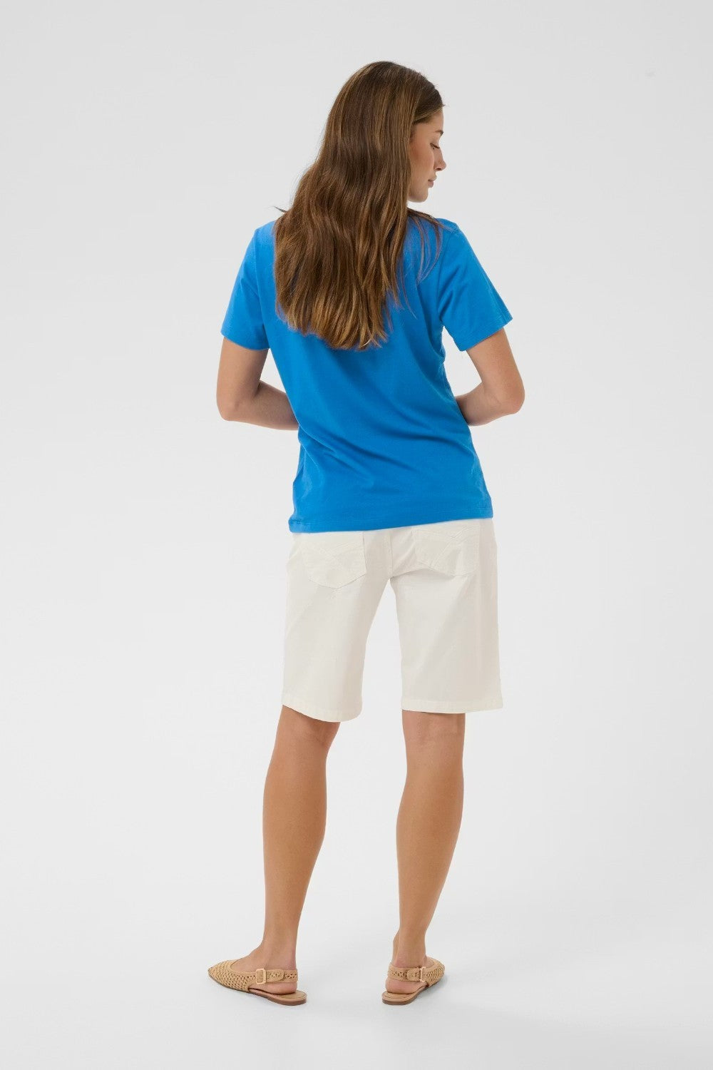 Person wearing a blue shirt and white shorts on a light gray background