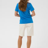 Person wearing a blue shirt and white shorts on a light gray background