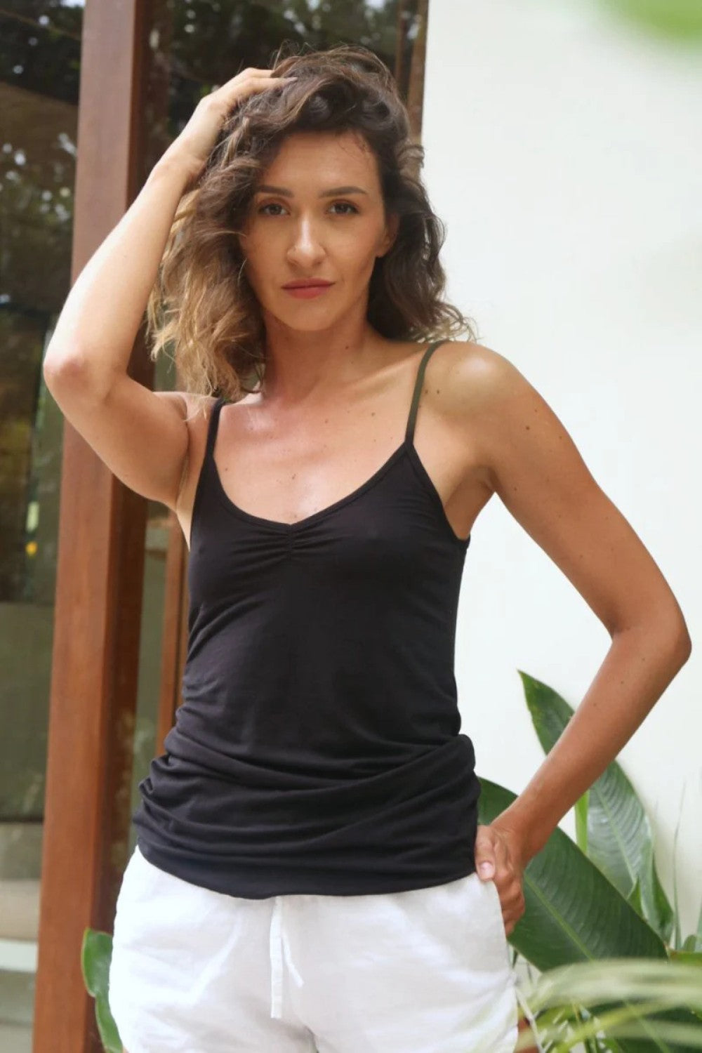 Woman wearing a black tank top and white pants outdoors
