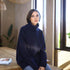 Woman wearing a navy blue sweater sitting on a wooden bench indoors.