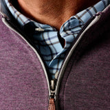 Close-up of a person wearing a purple zip-up sweatshirt over a plaid shirt.