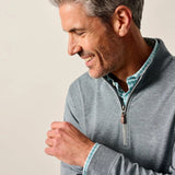 Man wearing a gray zip-up sweatshirt against a plain background