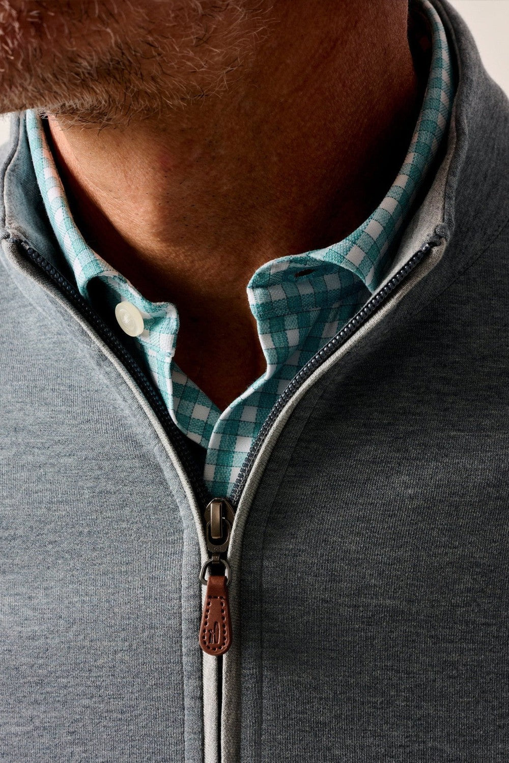 Close-up of a person wearing a gray zip-up sweatshirt with a checkered collar.