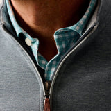 Close-up of a person wearing a gray zip-up sweatshirt with a checkered collar.