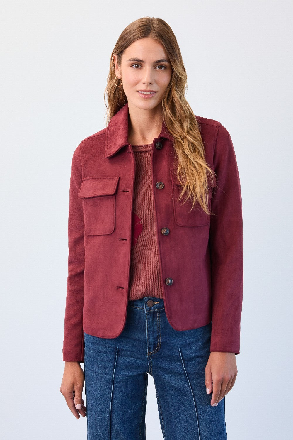 Woman wearing a red jacket and blue jeans against a white background