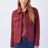 Woman wearing a red jacket and blue jeans against a white background
