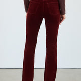 Maroon velvet pants worn by a person on a white background