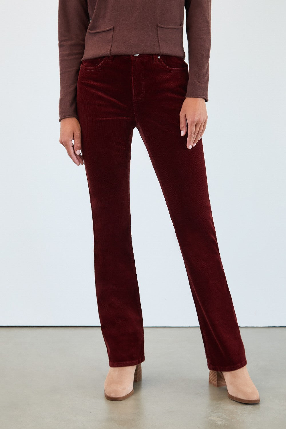 Person wearing burgundy velvet pants with a plain background