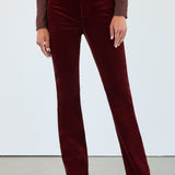 Person wearing burgundy velvet pants with a plain background