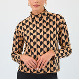 Woman wearing a patterned top with black and beige design on a plain background