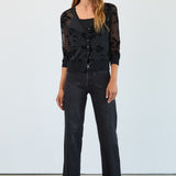 Woman wearing a black floral top and jeans against a white background
