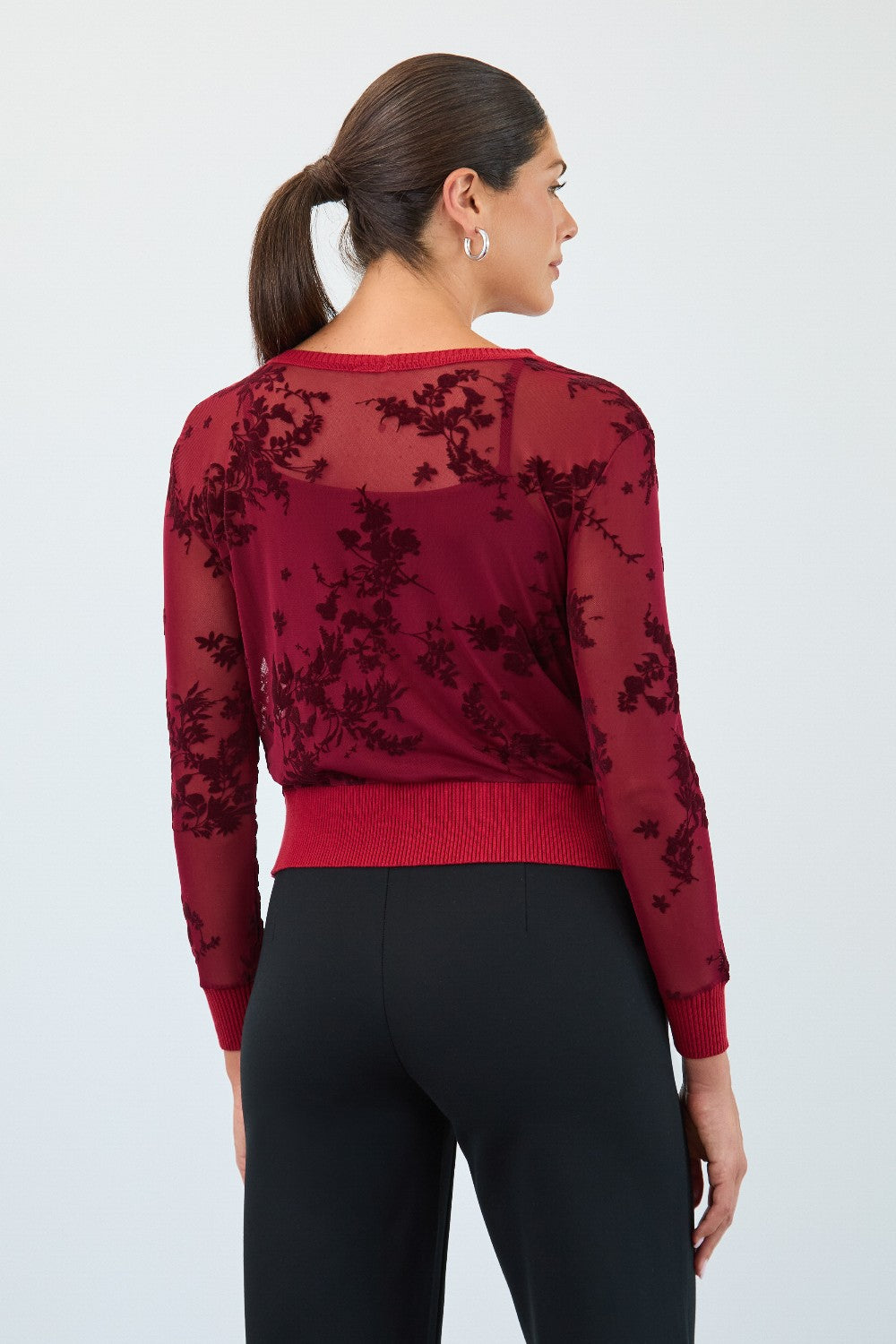 Woman wearing a red sweater with floral lace details on a white background