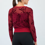 Woman wearing a red sweater with floral lace details on a white background