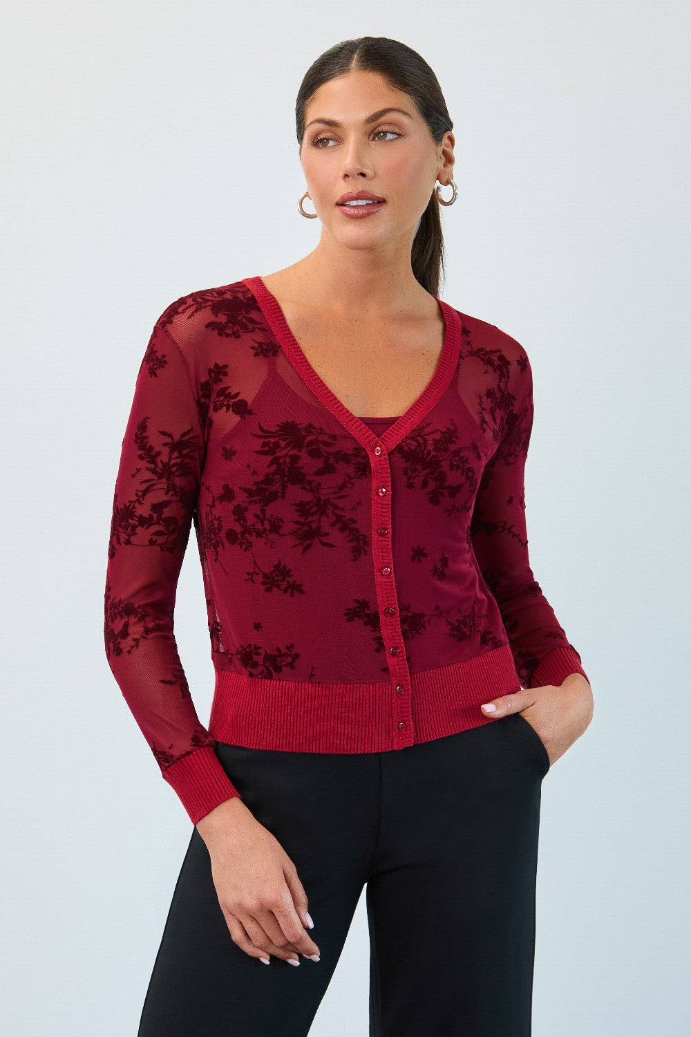 Woman wearing a red floral cardigan against a light gray background