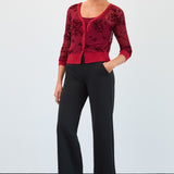 Woman wearing a red floral top and black pants against a white background