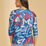 Woman wearing a blue graphic top with red and white on a beige background