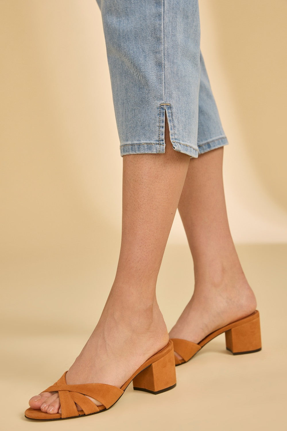 Brown block-heel sandals worn with light blue denim shorts on a beige background