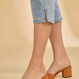 Brown block-heel sandals worn with light blue denim shorts on a beige background