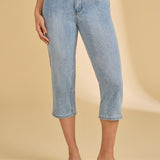 Person wearing light blue jeans on a beige background