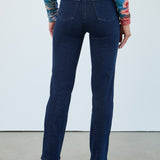 Person wearing blue jeans and a colorful top on a plain background