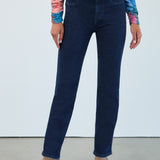 Person wearing dark blue jeans and a colorful top against a white background