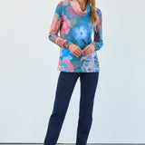 Woman wearing a colourful floral top and blue jeans against a white background