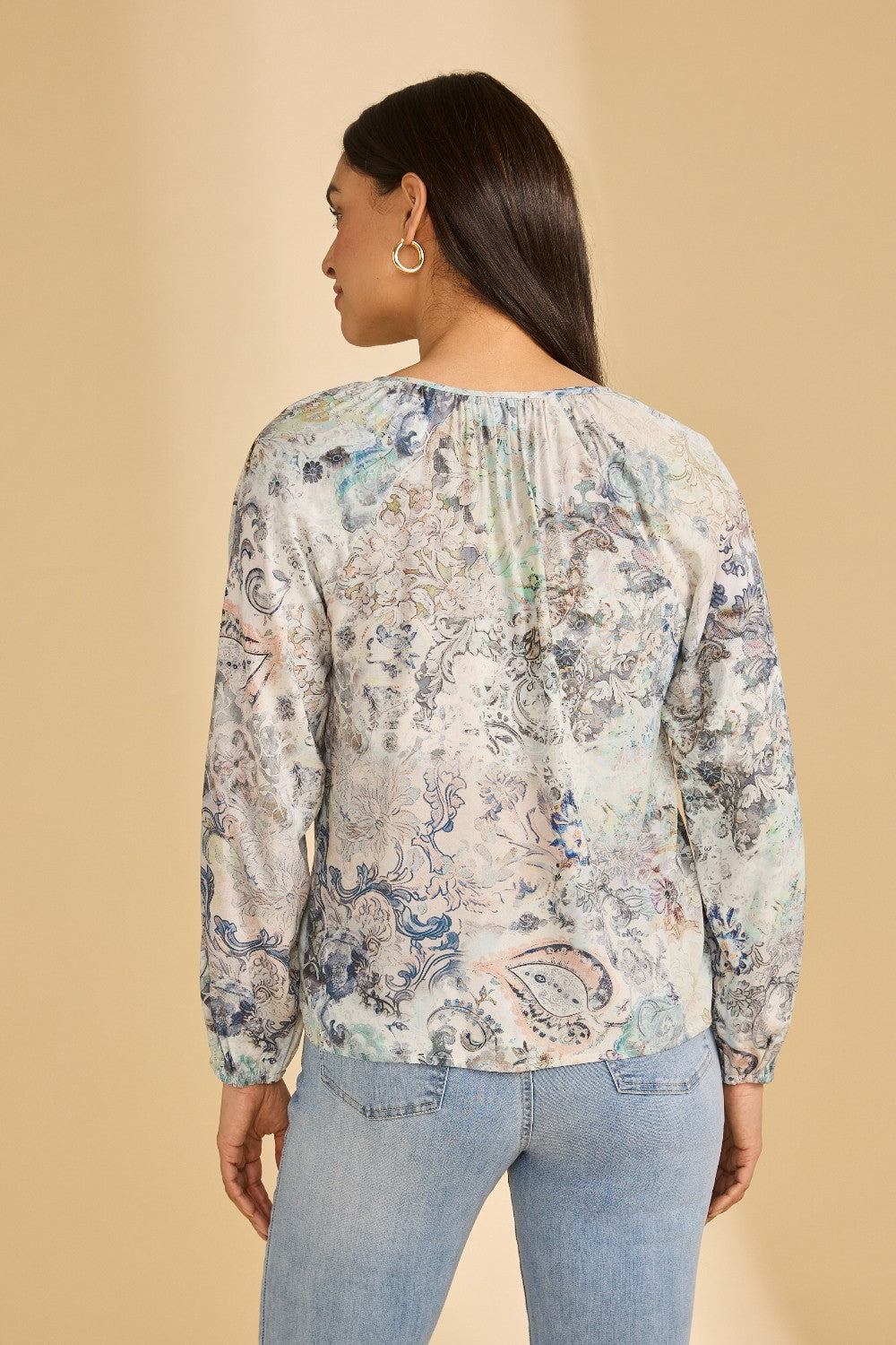 Woman wearing a floral blouse with long sleeves on a beige background