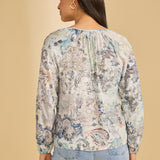 Woman wearing a floral blouse with long sleeves on a beige background